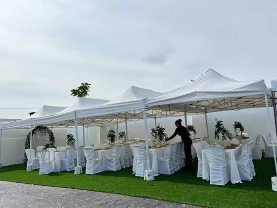 Carpas blancas con mesas y sillas vestidas montadas para un banquete de boda en jardín