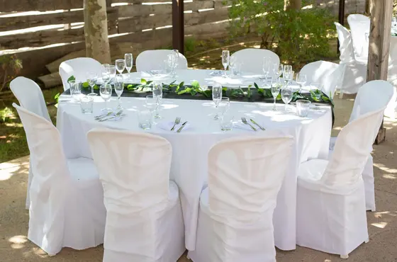 Mesa redonda con mantel blanco, camino negro con hiedra y cristalería, montaje de banquete