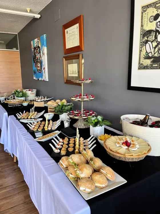 Buffet largo con torre de postres de frambuesa, mini bocadillos, canapés y tabla de quesos para empresa en Valencia
