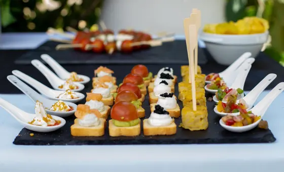 Canapés de salmón, aguacate y tomate, caviar, tortilla y cucharas de degustación sobre pizarra