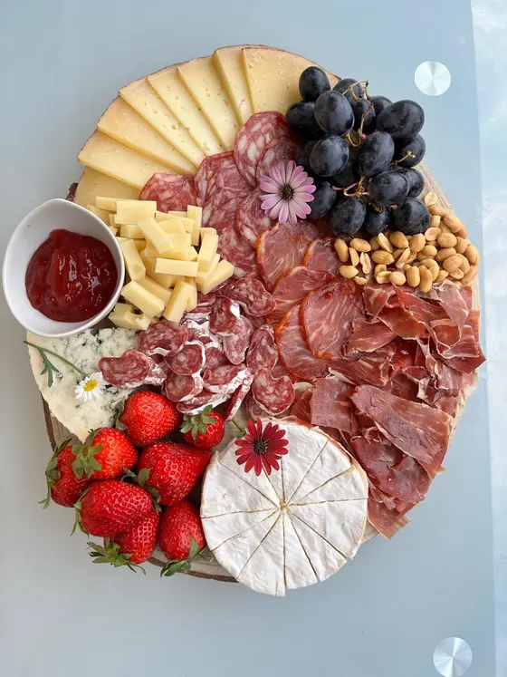 Tabla redonda de quesos, jamón ibérico, embutidos, fresas, uvas y mermelada