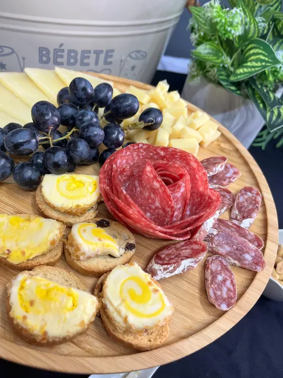 Tabla con rosa de salchichón, queso, uvas negras y tostas de queso de cabra