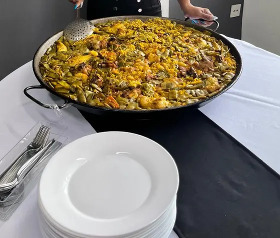 Paella valenciana de verduras y carne en paellera grande para un evento en Valencia