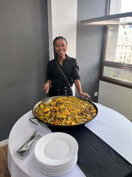 Triana, de Bon Menjar, sonriendo junto a una paella valenciana en un evento en Valencia